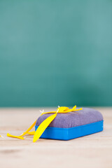 A blackboard eraser and scattered yellow petals on the desk in front of the blackboard