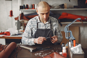 Man working with leather. Professional makes a holes. Man upaints the leather.