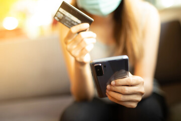 A woman wear a mask is shopping online via credit card in Coffee cafe