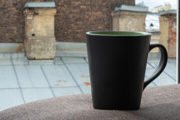 Obraz premium a Cup of morning coffee on the roof of an old house with brick chimneys in a big city