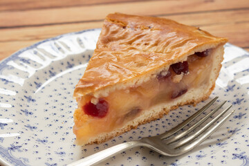 Traditional homemade apple pie with cranberries. Individual portion of the cake on a plate with cutlery on a wooden table