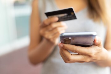 A woman holding a phone and dialing a credit card code online to payment for shopping online.