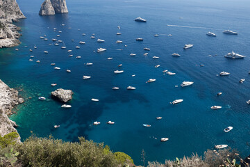 Fototapeta na wymiar View from Augustus Gardens viewpoint and boats sailing around in crystal waters of the Tyrrhenian sea, Capri Island, Italy