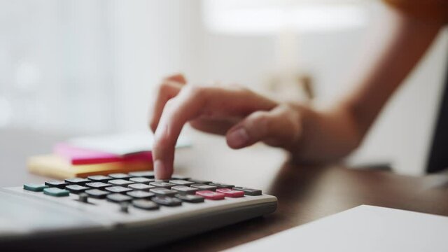 Hand press calculator to calculate income expenses and plans for spending money on home office.