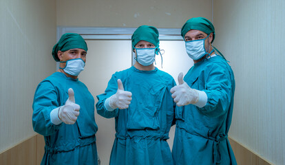 Fototapeta na wymiar Portrait team of doctors surgeons wearing uniform and medical mask show safety from virus in hospital show hand in good signal with work