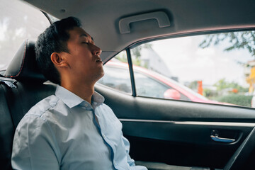 Tired businessman asleep in back seat of car, resting, on the move, business travel, sleeping