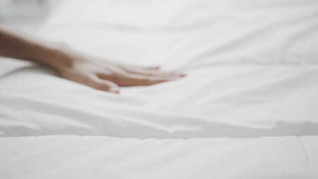 Hand touching very soft on a wrinkled white cloth and swept it down completely.