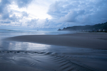 Creek water flowing from uphill into the ocean beautiful reflections in the clouds after sunset