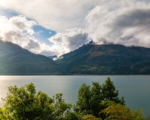 Golden hour at Lake Wanaka with the mountain range engulfed in clouds in Mount Aspiring National...
