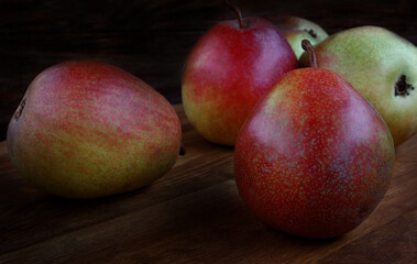 Several ripe pears lie on a wooden board.
