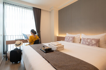 Tourist woman reading book in bedroom after check-in and arrival at a hotel.