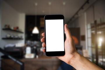 Mockup image of hand holding white mobile phone with blank white screen in cafe.