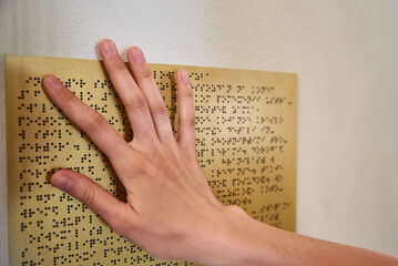 Woman reading braille text on braille plate - obrazy, fototapety, plakaty