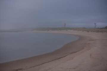 Expanse of sand at the beach. Low visibility due to fog and overcast day