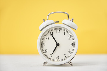 Time concept. White retro alarm clock on yellow background with copy space. Time concept