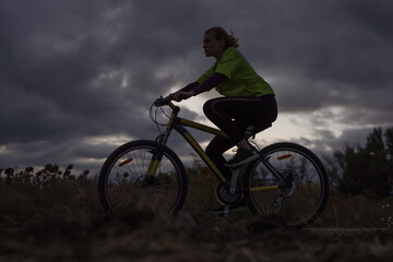 Fototapeta na wymiar Sport woman bicycling against dramatic sky background