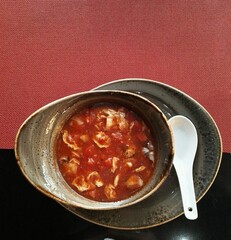 Red tomato soup with seafood on a red background.
