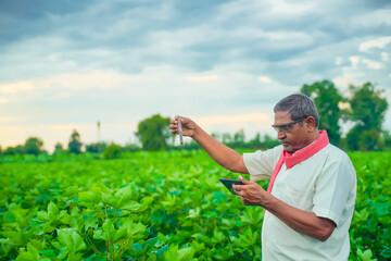 indian farmer checking with test tube and tablet at field