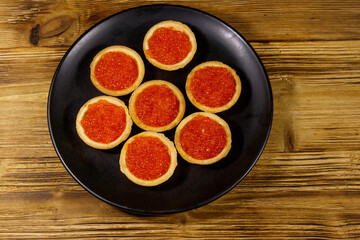 Tartlets with red caviar on a wooden table. Top view