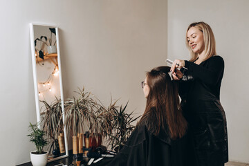 A female hairdresser of European appearance works with the hair of a model. Home beauty salon....