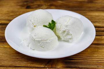 Vanilla ice cream in white plate on a wooden table