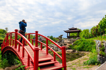 Fototapeta na wymiar Travel photographer man with professional camera taking photos of Japanese garden