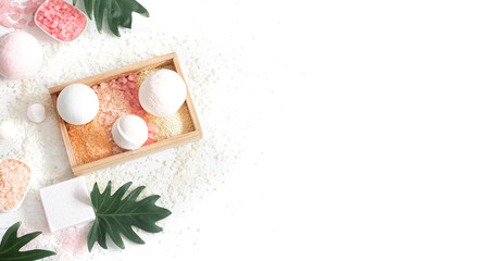 Composition with multi colored sea salt and bath bombs on a white background.