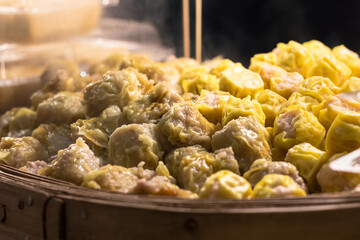 Dumplings steaming hot in a wicker basket.