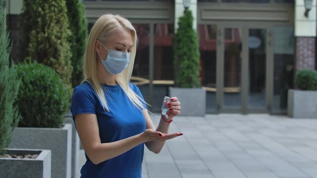 Side view of a woman disinfects her hands with an antiseptic bactericidal gel. Corona virus health protection concept. Slow motion. Close up outdoors on a street background.