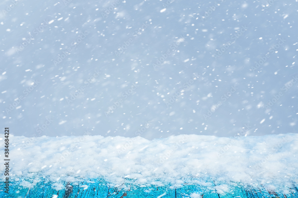 Poster winter abstract background with snow-covered table and snowflakes on blurred background