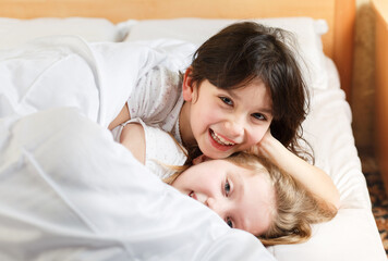sisters playing in the bedroom on the bed