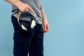 Headphones in man hands cropped view music technology blue background