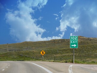 Directional roadside signs with an arrow to Exit 102 at Highway 90 just past Gillette, Wyoming.