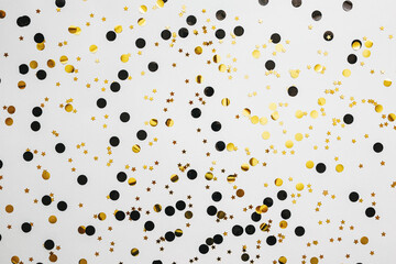Scattered golden and silver confetti on a white abstract festive background.