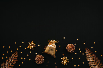 Various festive items and decorations in gold color on a dark or black background. Top space for text or copy space. Christmas or New Year's concept.