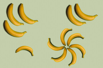 Fruit pattern. Repetition of whole bananas of different sizes on a light green background. Interesting fruit pattern made from natural fruits. Horizontal. The concept of healthy food and vegetarianism
