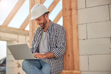 Ambitious field engineer working on his laptop near a building