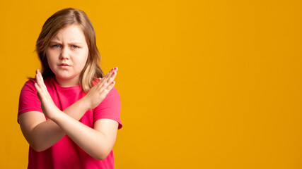 Stop gesture. Child protest. Offer rejection. No answer. Disturbed young girl in pink showing X...