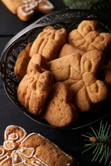 Tasty homemade cookies with icing on dark table with fir branch. Christmas and winter concept
