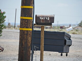 Old mailbox near a power post by the roadside in the desert