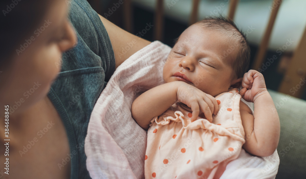 Wall mural newborn baby sleeping in safety while mother is holding and smiling at her