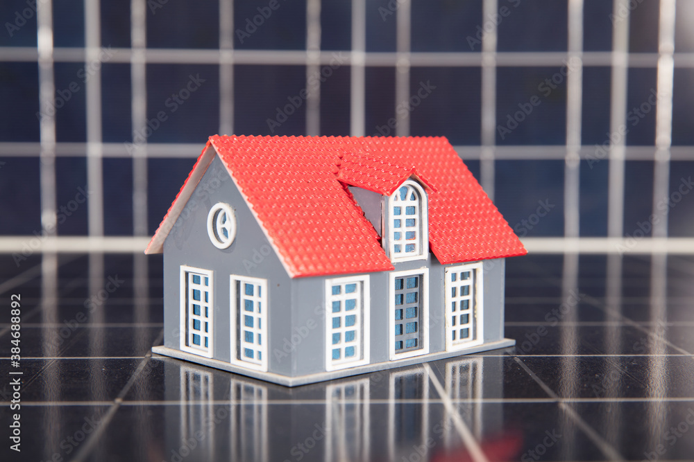 Wall mural a small house model placed on a background of solar panels