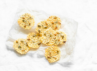 Homemade cheese chips with pumpkin seeds on a light background, top view