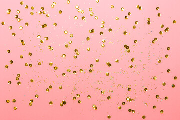 Pink background with gold sequins and shining paillettes. Festive backdrop for your projects. Top view, copy space