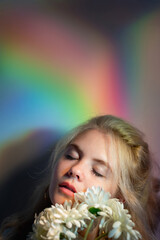 Nature portrait. Freshness wellness. Ayurveda spa. Tranquil blonde woman with closed eyes flowers on blur rainbow color gradient glowing iridescent light empty space background.