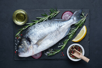 Raw dorado fish with olive oil, rosemary and spices on cutting board. Top view composition