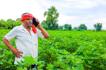 young indian farmer using smartphone at field