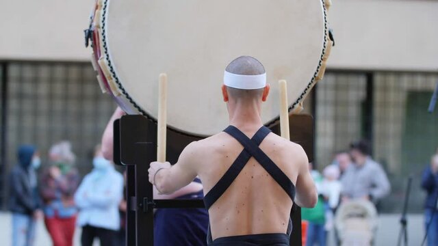 Man with Headband Playing Vertical Drum of Japanese Musical Tradition during a Public Outdoor Event