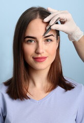 Fototapeta premium Young woman undergoing eyebrow correction procedure on color background