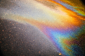 Abstract rainbow effect background, colorful gas stain on wet asphalt caused by a leak under a car or truck